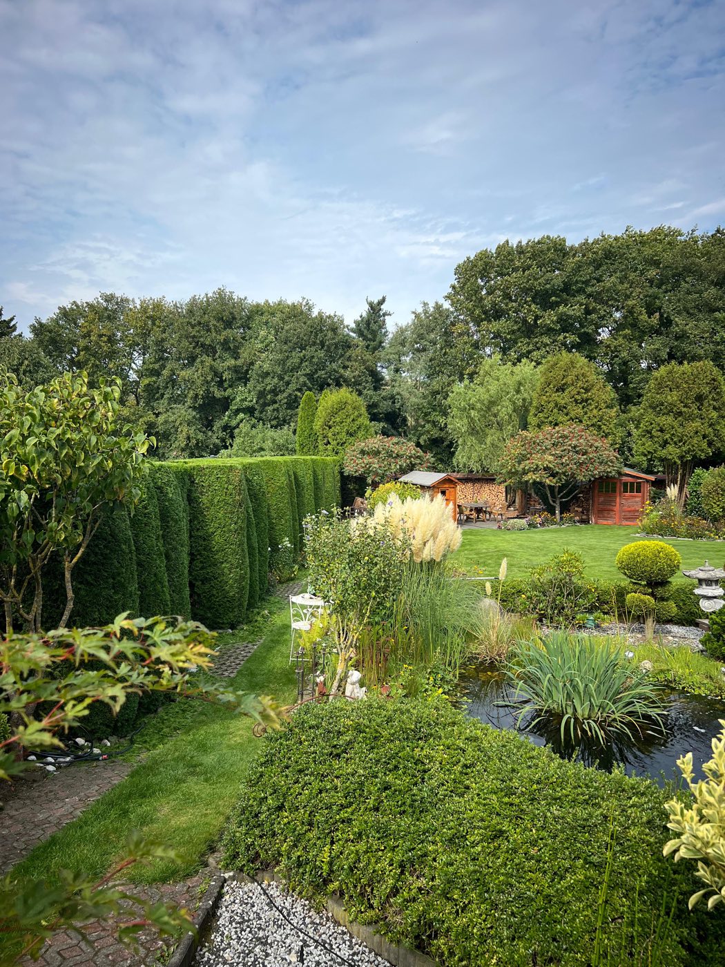 Gepflegter Garten mit geschnittenen Formgehölzen, Hecke und Gartenteich