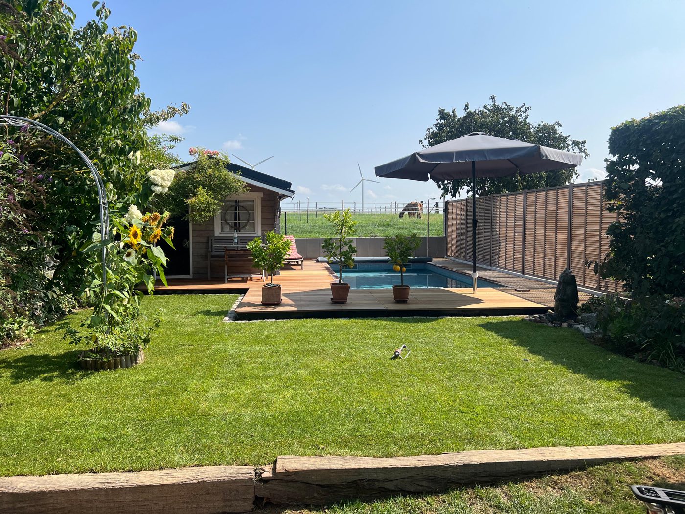 Garten mit Holzdeck am Pool, Sichtschutzzaun, Graniteinfassung und neu verlegtem Rasen